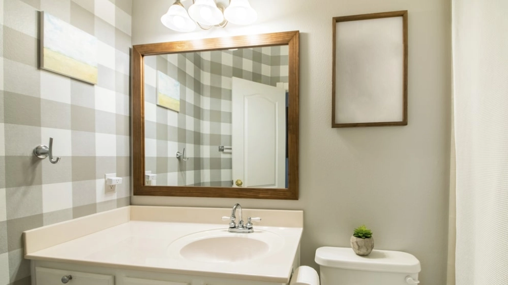 neutral-tone bathroom with mirrored vanity and wallpaper