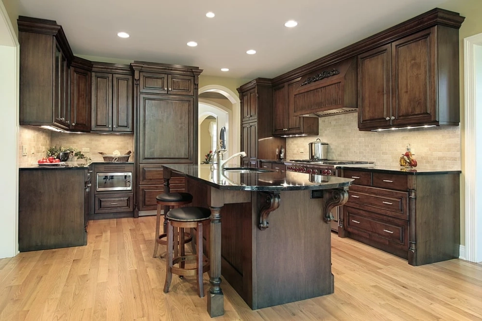 stained wood kitchen cabinet with beaded doors and black marble counter