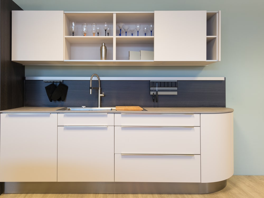 curved base cabinet door and upper open shelves at the white cabinet set