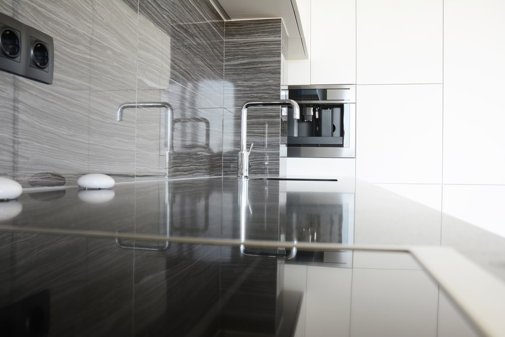 dark quartz countertop kitchen with tiling backsplash and white cabinets
