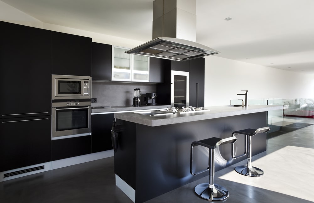 open plan kitchen with black cabinets and stainless steel appliances