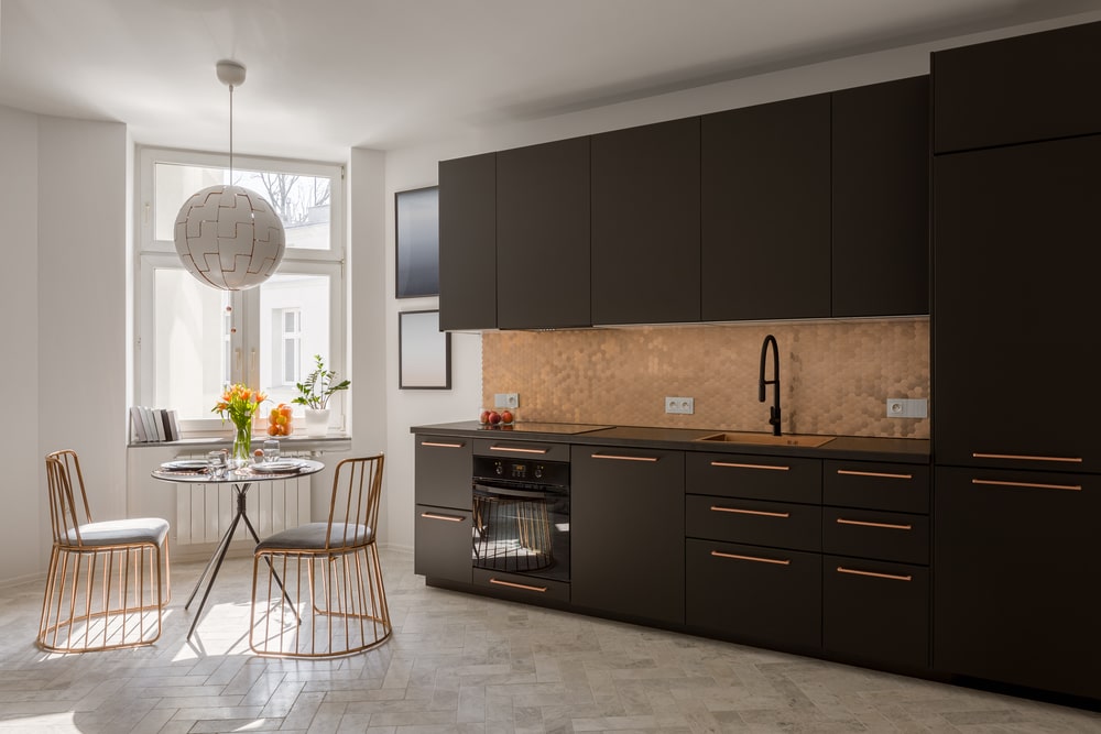 open space kitchen with black cabinets and copper handles