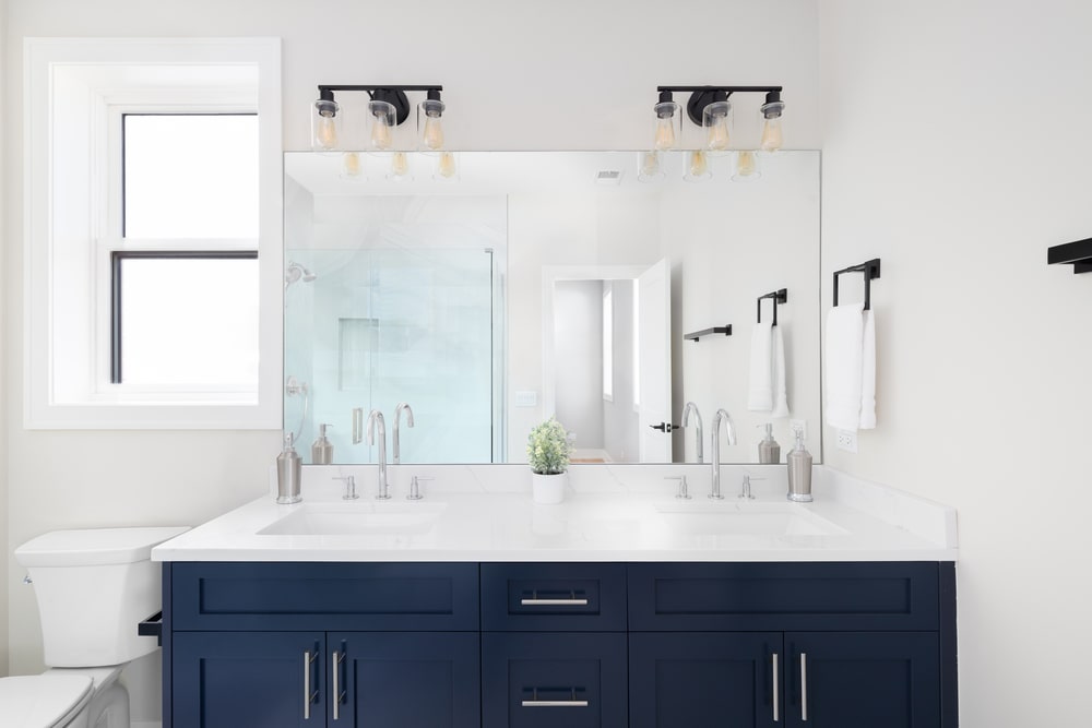 Chrome cabinet hardware and black towel holder mix in the bathroom with blue vanity