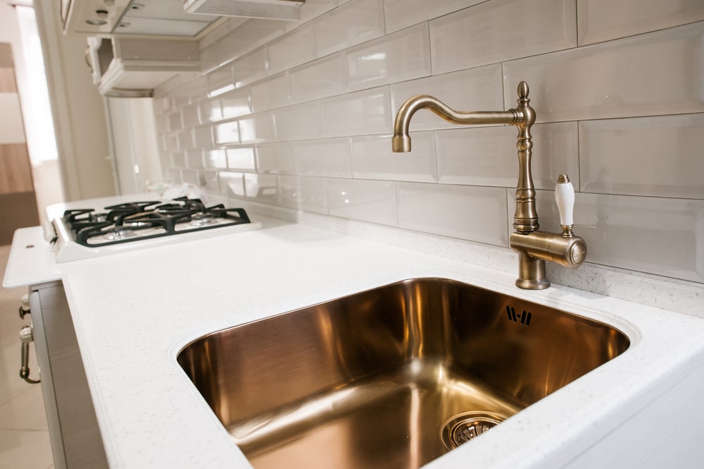 copper sink and faucet in the white kitchen