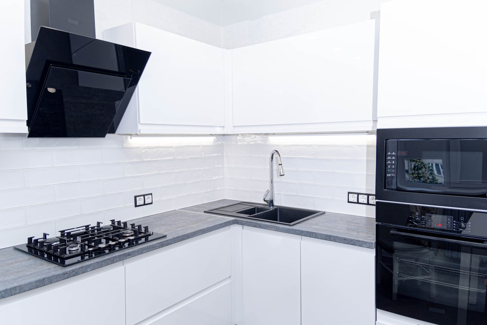 white kitchen j-pull handle doors with modern black appliances