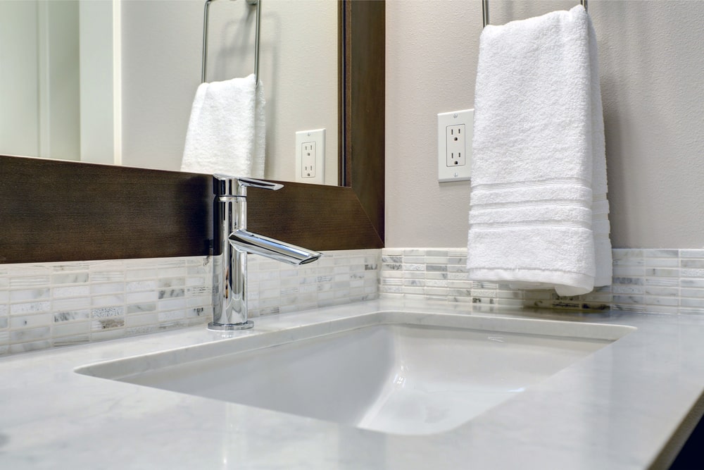 bathroom sink with 4' mosaic backsplash, mirror and towel