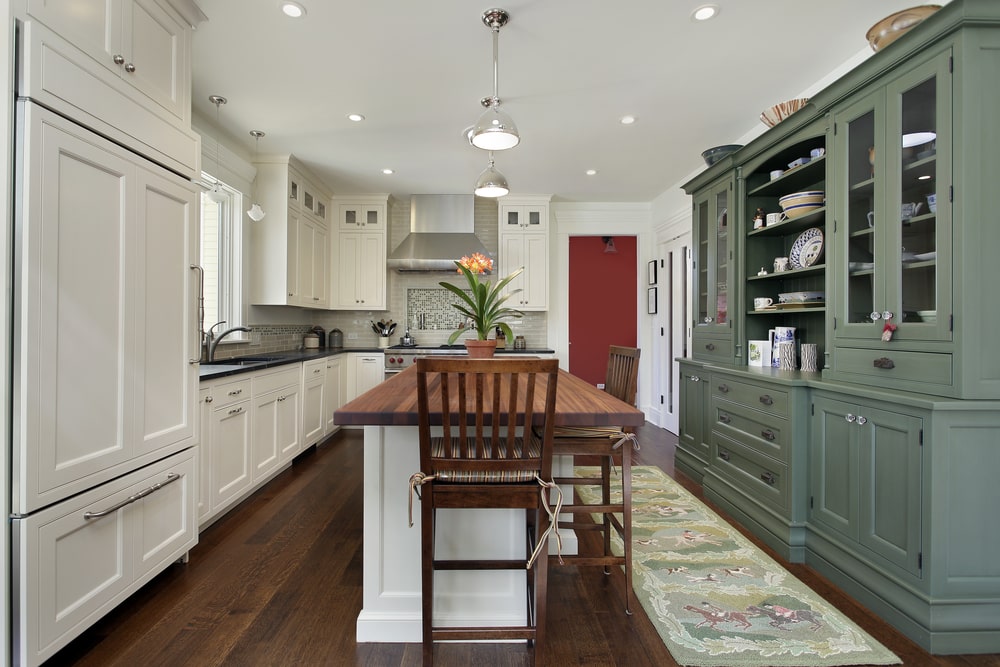 two-tone recessed-panel cabinets white and green and a wood island in the kitchen