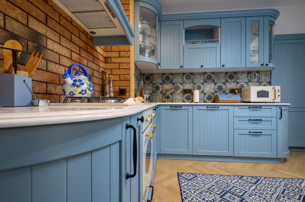 brick backsplash and blue beaded panel cabinet doors in the kitchen