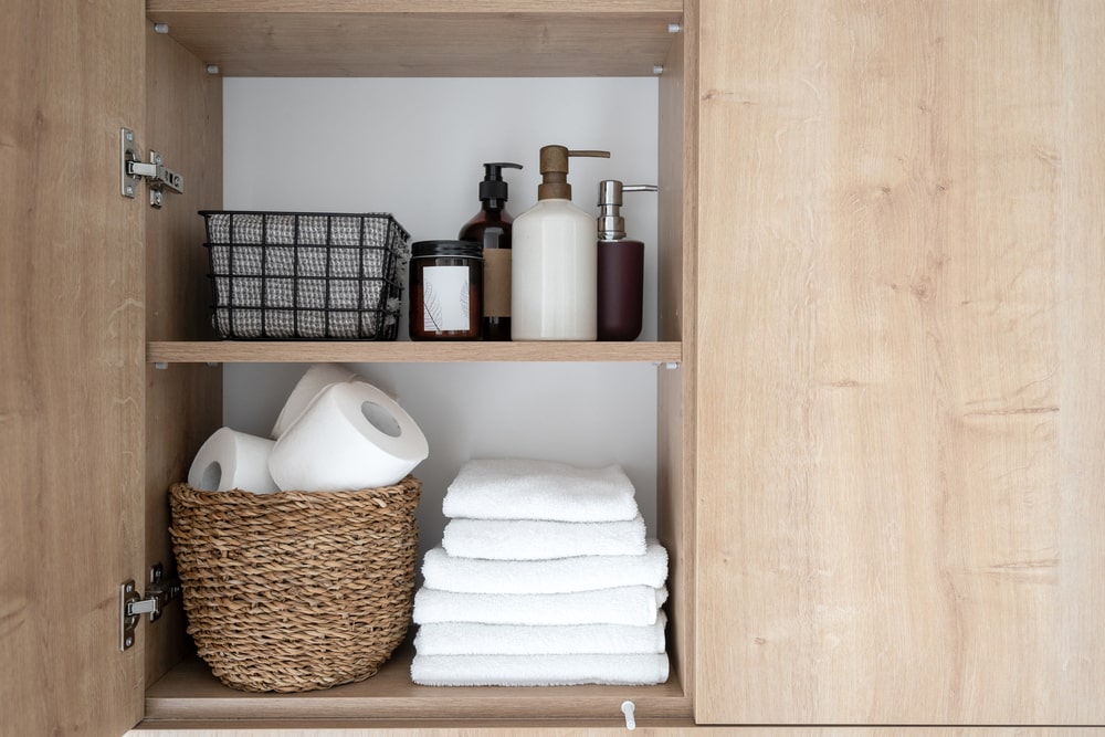 bathroom cabinet with organizing basket and container inside