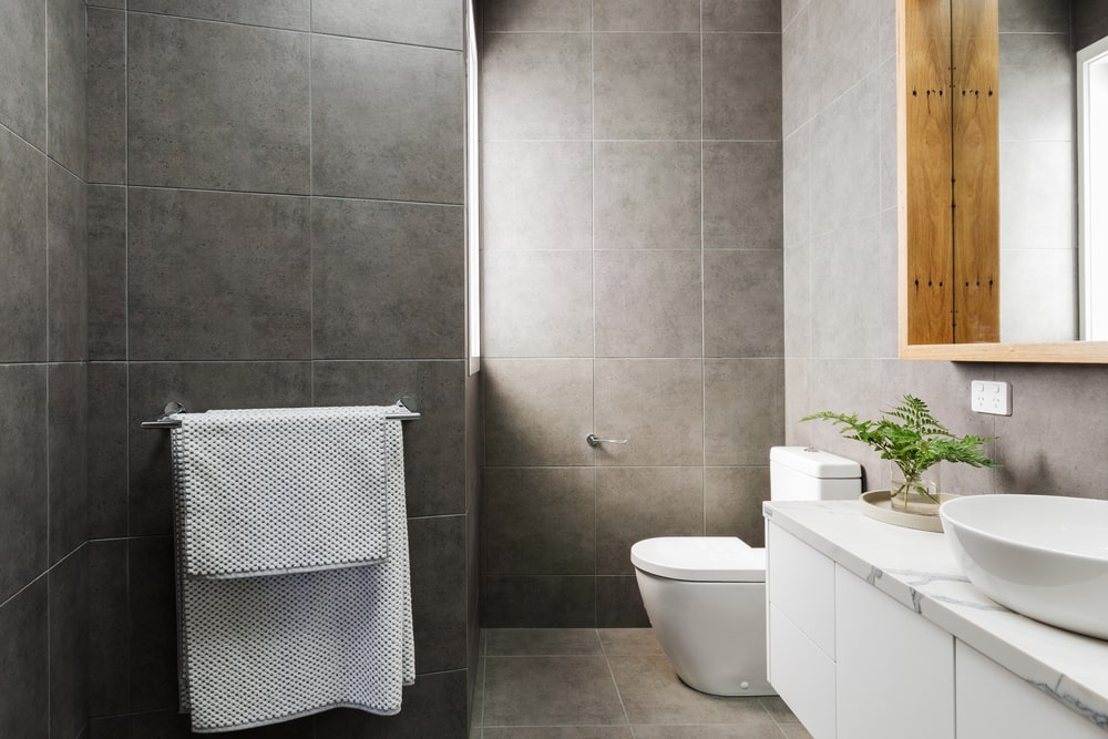 tiny ensuite bathroom with grey wall tile and white vanity