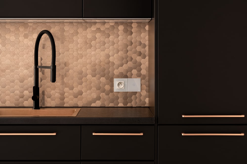 black kitchen cabinets with copper backsplash and sink