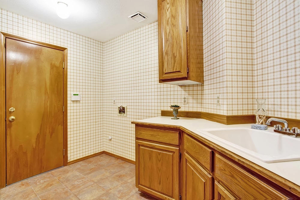 wooden cabinets and checkered wallpaper in the bathroom